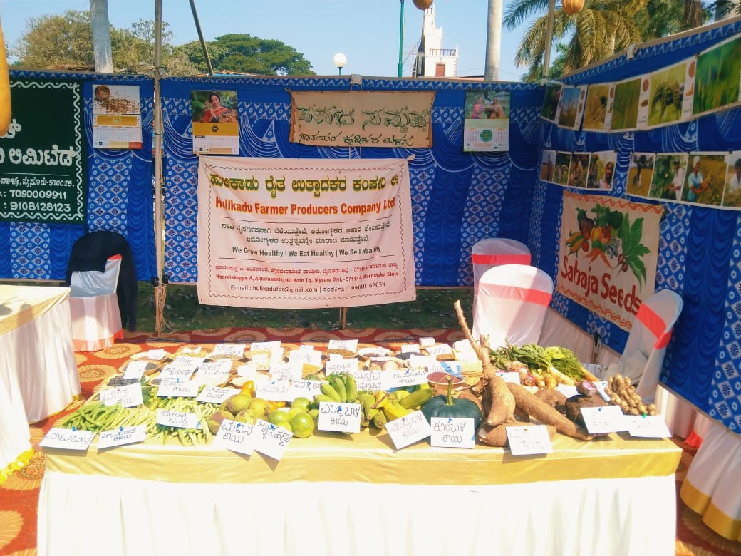 Hulikadu FPC stall displaying tubers and produce at an agricultural mela